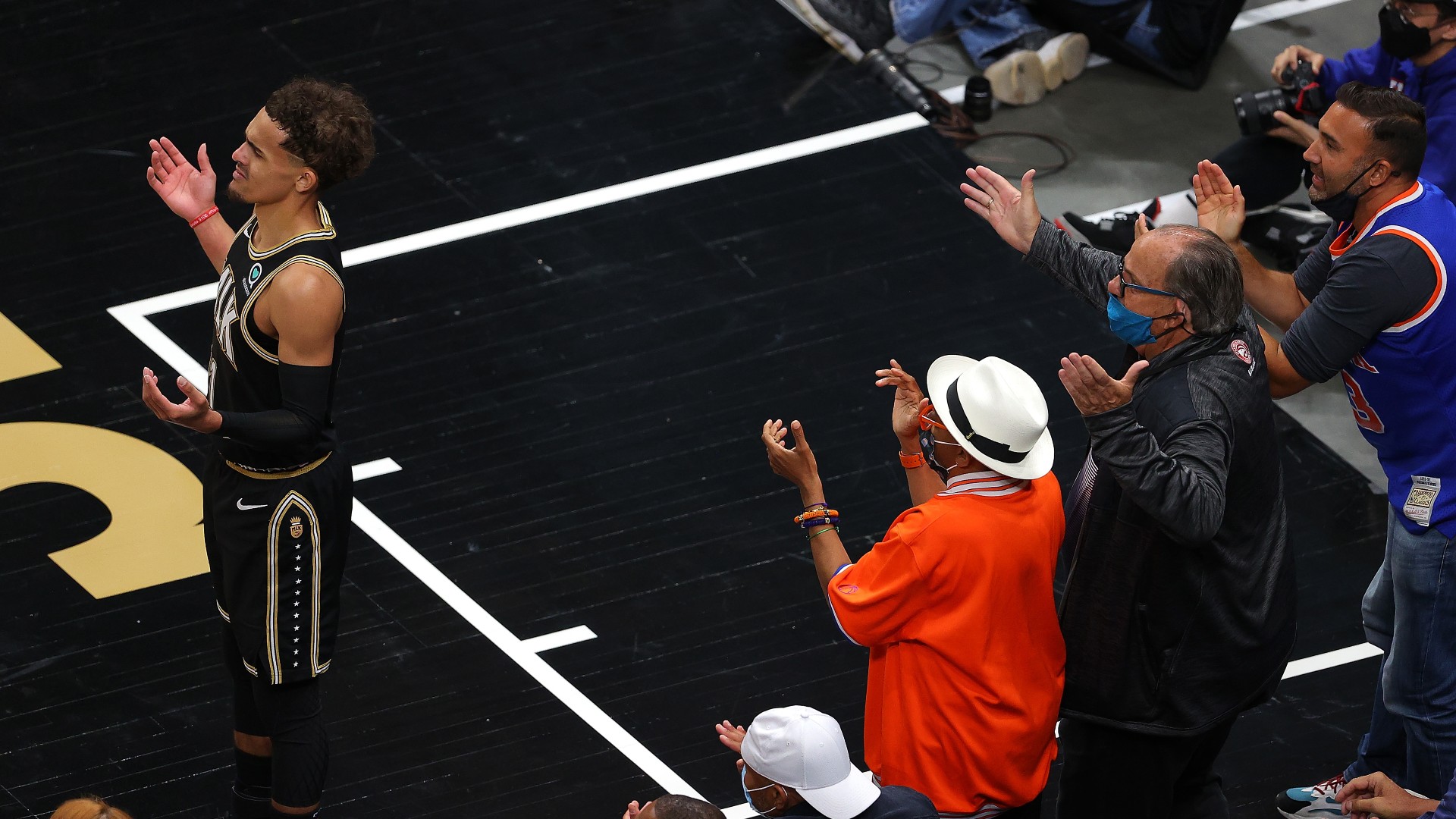 Trae Young reacts to a call during the 2021 playoffs while Spike Lee looks on.